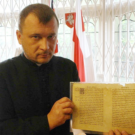 а. Сяргей Сурыновіч трымае Біблію Скарыны